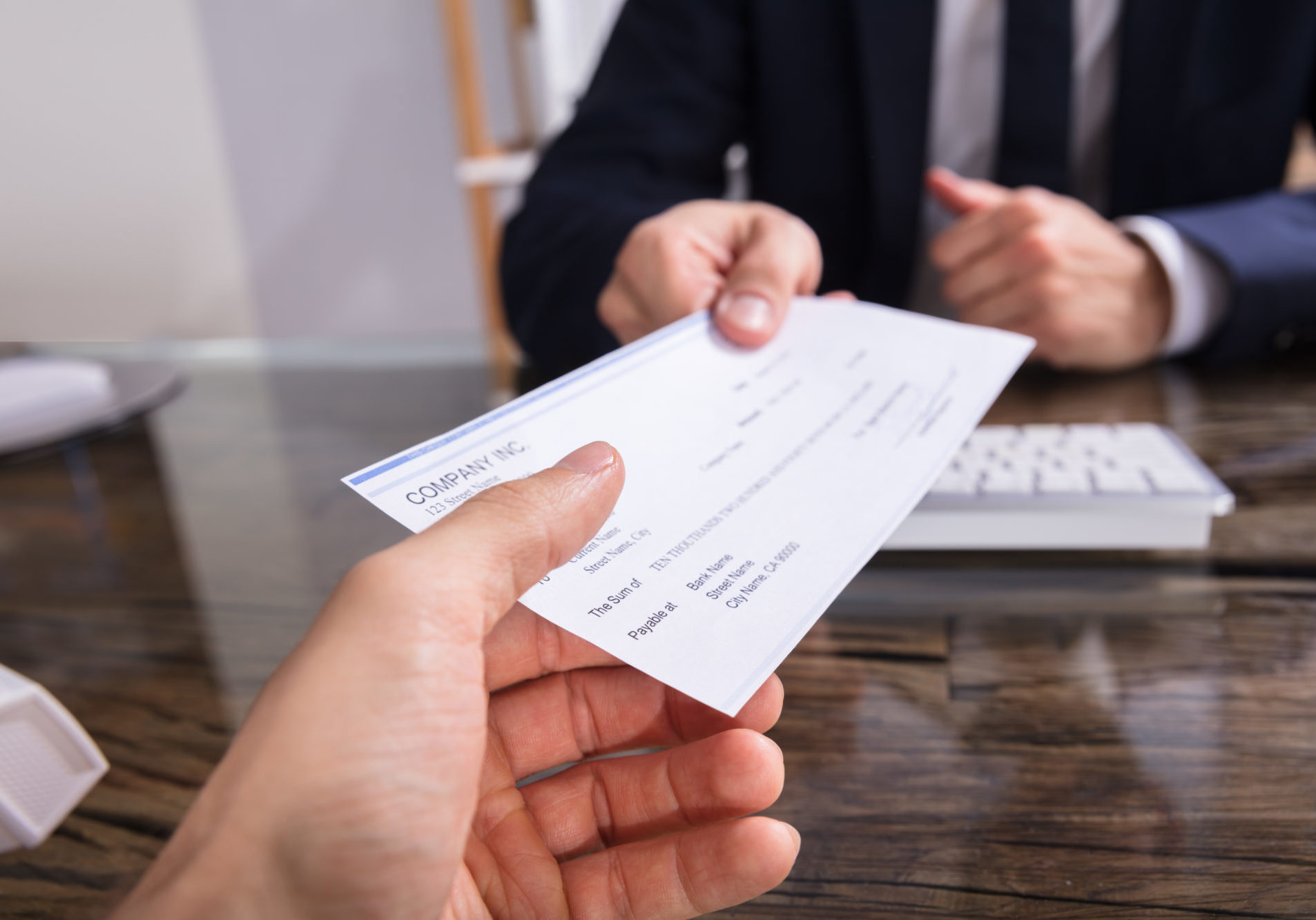 Close Up,Of,A,Businessperson's,Hand,Giving,Cheque,To,Colleague,At